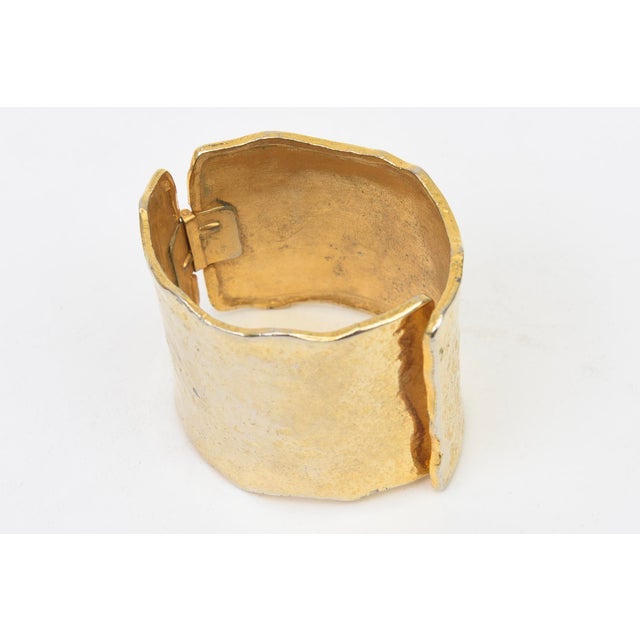 This vintage 1970's hand hammered gold plated cuff bracelet has an overlap closure in front with a scalloped edge. it is...
