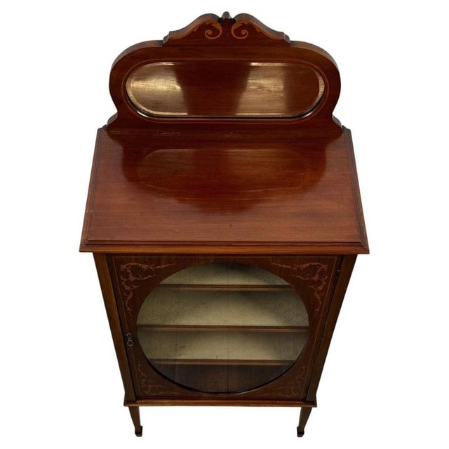 An elegant early 20th-century English display cabinet, finely crafted from mahogany and distinguished by its delicate...