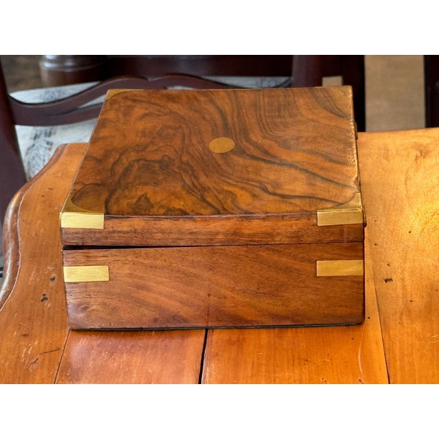 Rectangular box with a hinged lid, veneered throughout and fitted with brass corner mounts and an applied brass escutcheon...