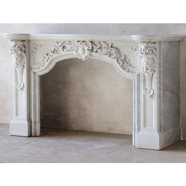 This exceptional, large, and exquisitely detailed fireplace is crafted from high-quality statuario bianco carrara marble....