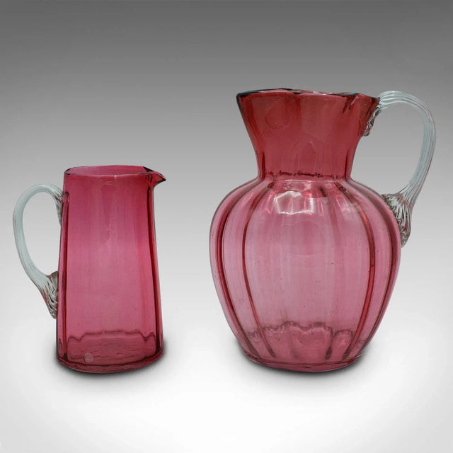 This is a vintage cordial mixer set. An English, cranberry glass pouring jug duo, dating to the early 20th century, circa...
