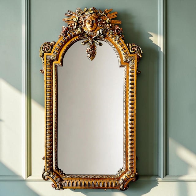 An ornate Louis XIV style gilt wall mirror designed by Vincenzo Fancelli for Franklin Mint, featuring a dramatic...
