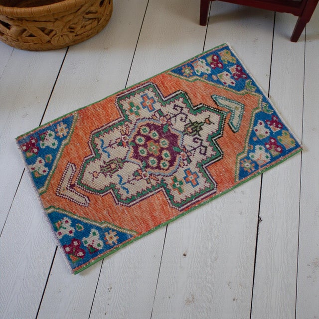 This vintage Oushak mat radiates warmth with its sun-faded terracotta field and striking deep blue accents. Its low-...