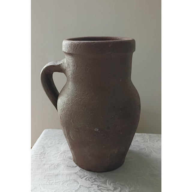 This charming vintage terracotta jug is a testament to the elegant simplicity of traditional Mediterranean or European...