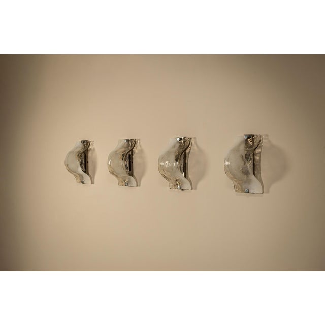 A refined play of glass, contour and light, this set of four lt 276 wall lamps brings together the tactile language of...