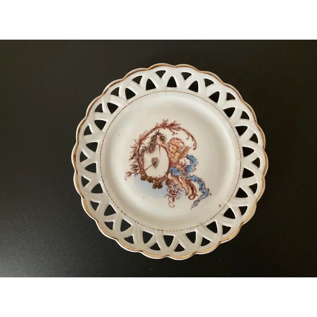 A beautiful and romantic cherub plate with lattice margin design from England, circa early 20th century. Plate has gold...