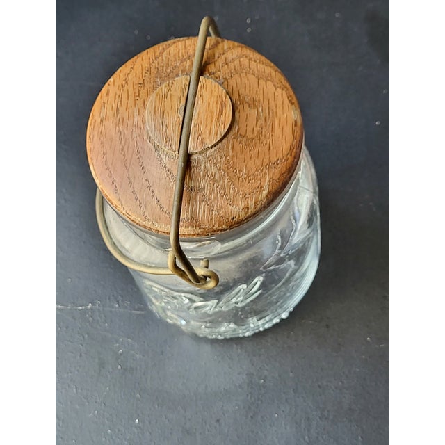 This beautiful vintage jar is made out of glass, wood and metal. It features a classic silhouette, and the wooden top can...