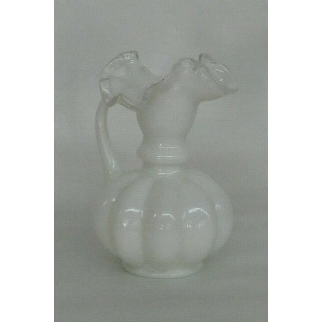 This adorable pitcher vase is made of glass. This vase is made of beautiful white opaque milk glass with the Silver Crest...