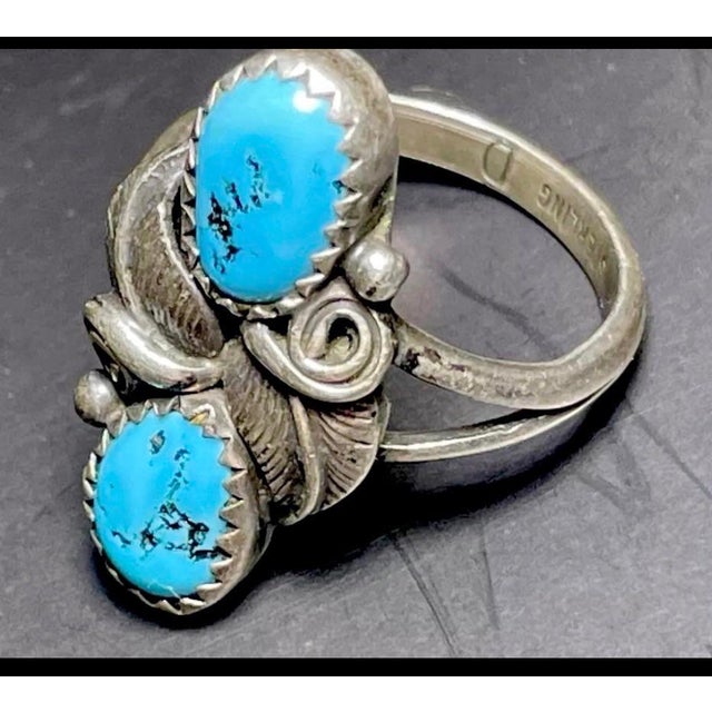 Native American double feather ring, stamped "D" by the Navajo artist, John Delvin. The ring displays two vibrant powdery...