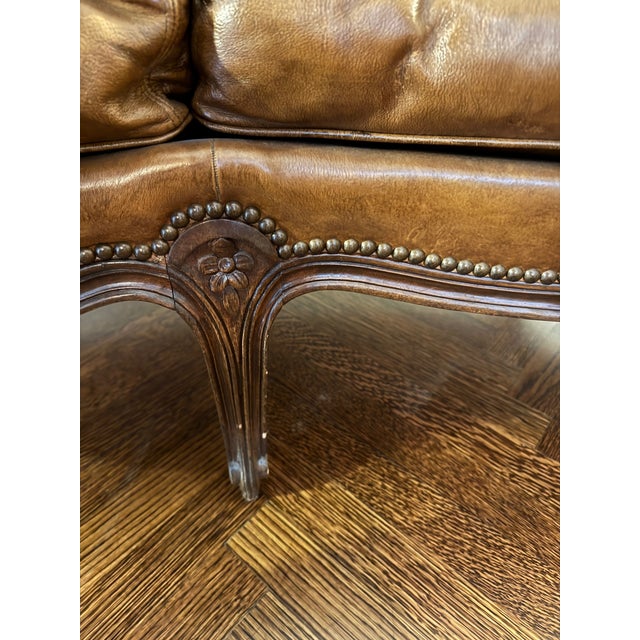 A beautifully coordinated salon set comprising a leather loveseat and matching pair of bergère armchairs, executed in the...