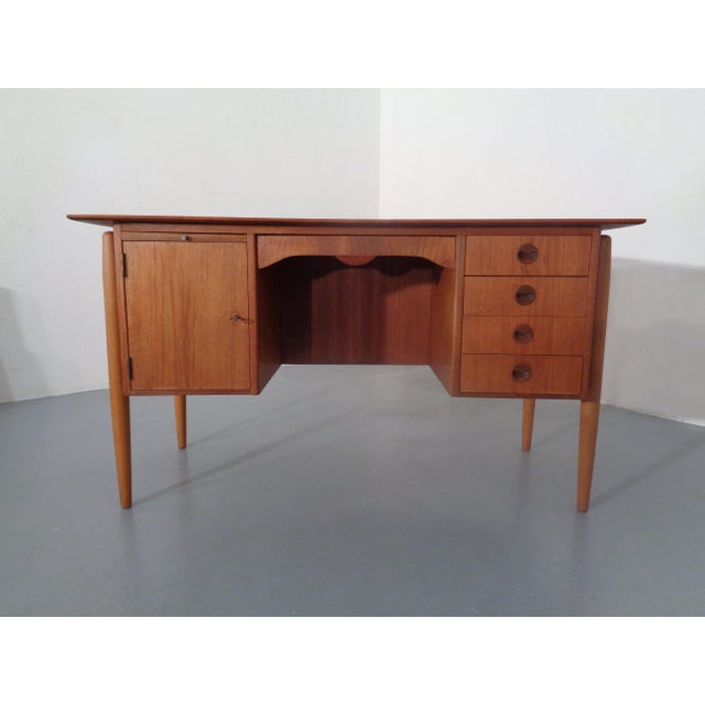 Small Danish teak desk from the 1960s. On the right side, there is a door. Behind it is a shelf. Above the door is a pull-...