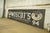 Reclaimed movie set sign made of aluminum in black, white, blue, brown, and yellow colors. The sign reads "Est. 1915,...