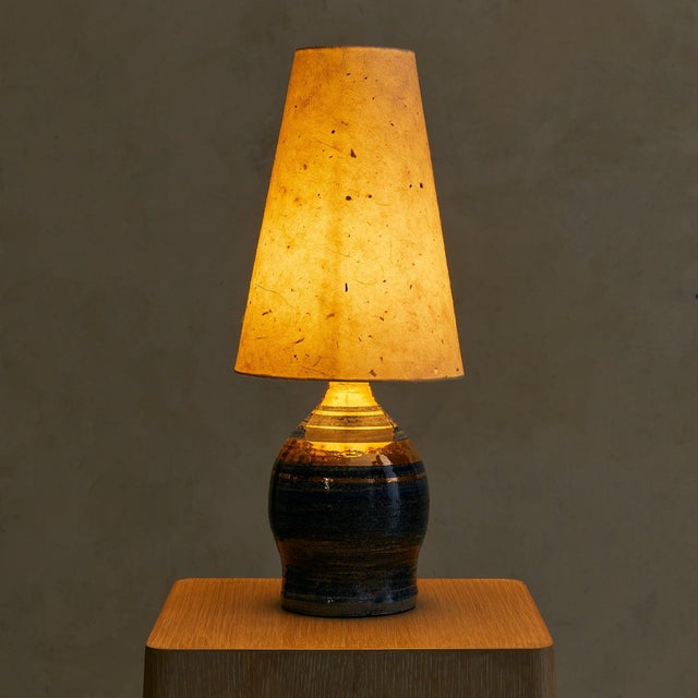 A 1960s French ceramic table lamp by Georges Pelletier, finished in deep midnight blue glaze layered with shimmering gilt...