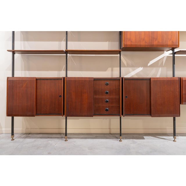 Italian modular shelving unit from the 1950s, made of wood and metal. The structure is supported by metal masts that are...