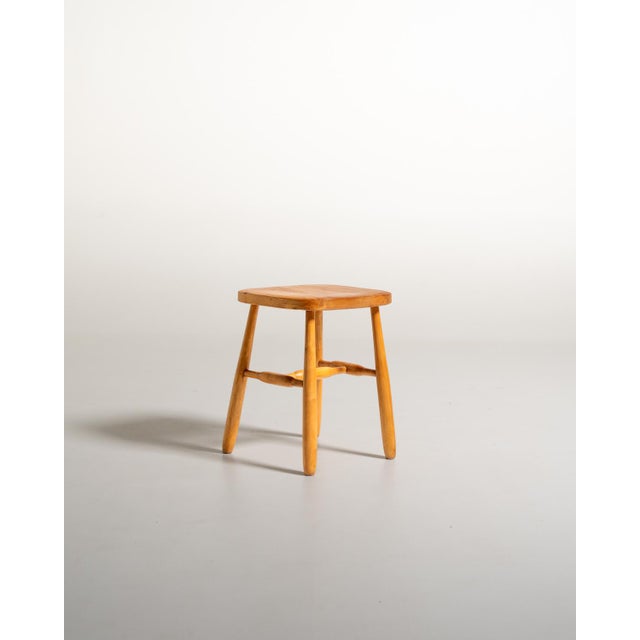 Scandinavian-made birch stool from the 1950s, featuring a square top with rounded corners, slightly splayed legs, and...