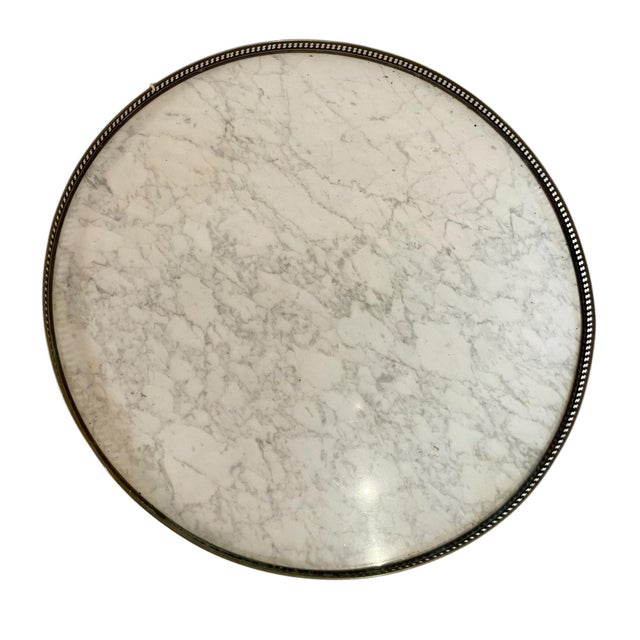 An exquisite brass side table featuring a luxurious round marble top with natural veining, the table is encircled by a...