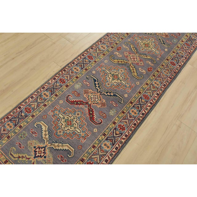 A tribal Caucasian Kazak runner hand-knotted with fine wool on a cotton foundation. This rug features a row of geometric...