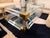 Jonathan Adler Jacques Grand Cocktail Table in clear acrylic, brushed brass and glass. One of Jonathan Adler’s signature...