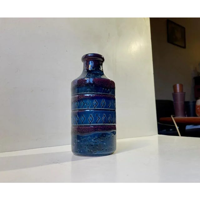 a high-gloss vase in chamotte clay. Executed in blue and purple glazes and featuring a center pattern of hand-incised...