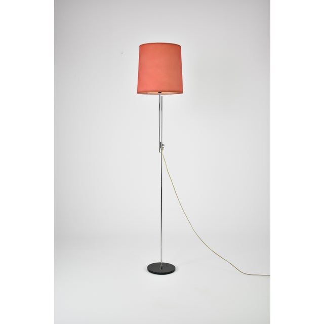 An Italian adjustable floor lamp from the 1960s, defined by its slender chromed structure, circular black base, and...