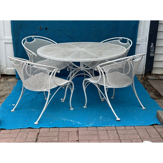 This robust outdoor dining set features a round mesh table paired with four matching chairs, all crafted from solid,...