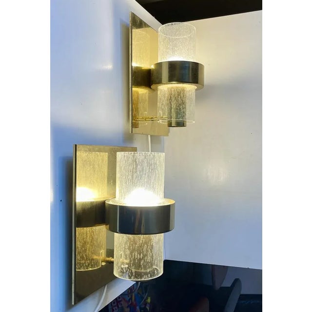 A pair of 1970s nautical - navy sconces composed of brass brackets set with cylindrical hand-blown tubes of rain-effect...