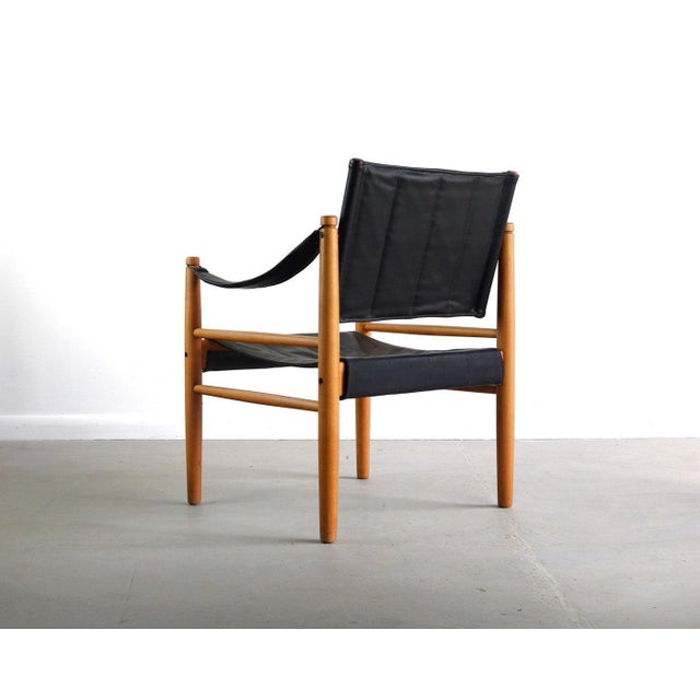 Stately safari chair in warm blonde wood and contrasting black upholstery. Sling style brings intrigue and comfort into...