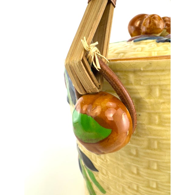 A charming vintage Japanese majolica biscuit jar featuring a molded basket-weave ground with colorful raised fruit and...