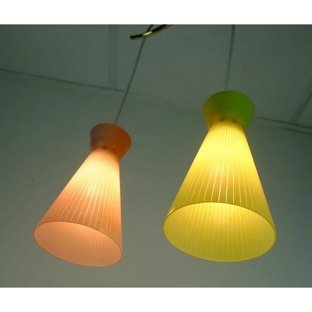 Hanging lamp from the 1950s with colored cylinder-shaped glass shades with a fine strip pattern, a pink and a lime green....