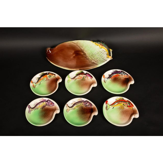 A delightful French mid-century hand-painted set comprising six fish plates and one platter, signed by the renowned...