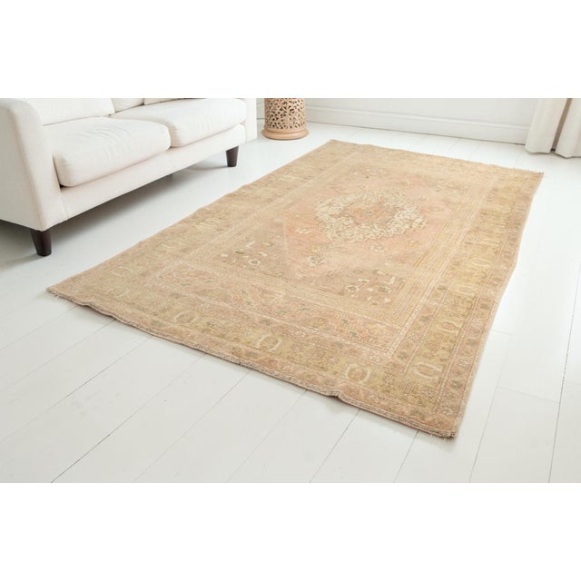 This is a vintage Turkish Oushak rug from the Mid 20th Century. The piece was hand-knotted.