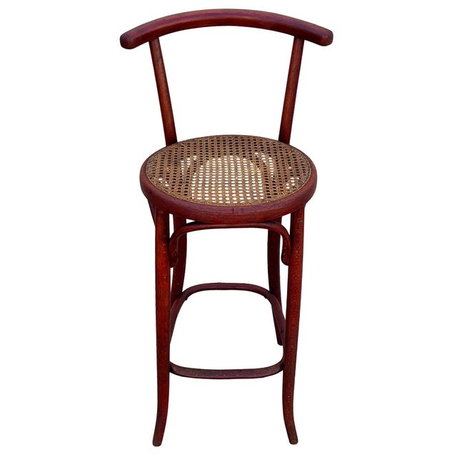 Victorian style cane and bent oak bar stool features an elegant, sculptural frame crafted from warm-toned bentwood with...