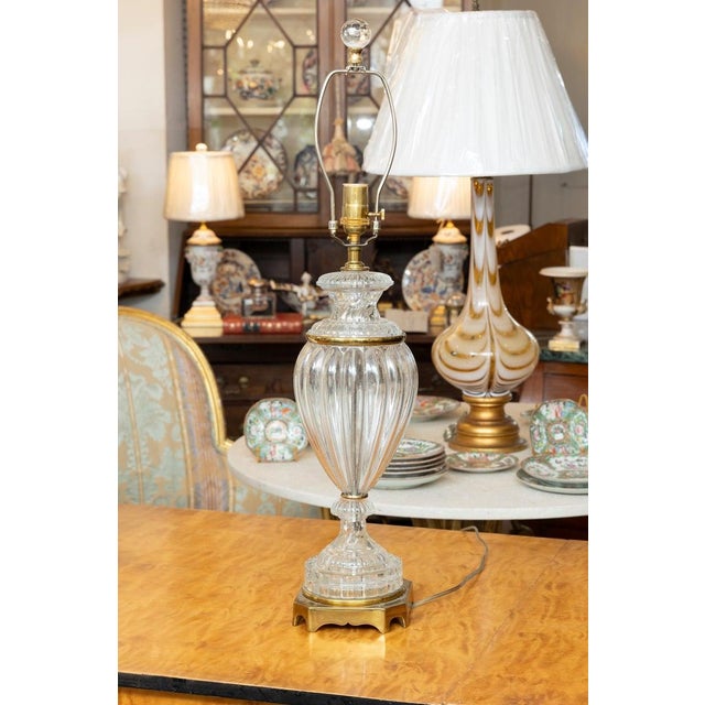 This is an elegant pair of French glass table lamps featuring hand-blown clear ribbed glass urn-form bodies with matching...