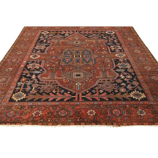 Covering a gracious 10x12 scale, a hand knotted wool antique Serapi rug originating from Persia circa 1920-1930, making...