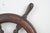 Vintage wood ship wheel with six spokes and a heavy brass center hub. It is characteristic of smaller maritime vessels or...