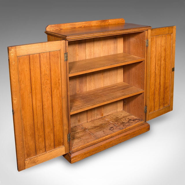 This is an antique side cabinet. An English, ash two-door book cupboard, dating to the late Victorian period, circa 1880....