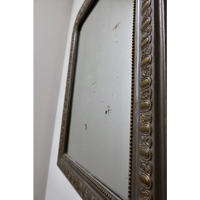 A beautiful antique French mirror in the Louis Philippe style, featuring an arched rectangular form with a repeating...