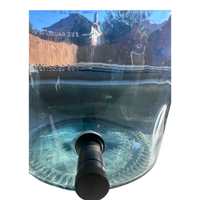 It is a luminous hand-blown Italian glass dispenser by SVE, celebrated for its sea-glass hue and fluid, organic form. The...