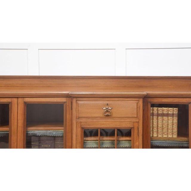 Arts and crafts walnut bookcase, the rectangular breakfront top having a raised gallery back, above three frieze drawers...