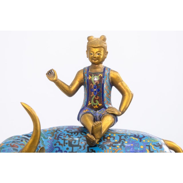A vintage Chinese cloisonne sculpture depicts a golden-horned bull adorned in rich blue enamel decorated with intricate...