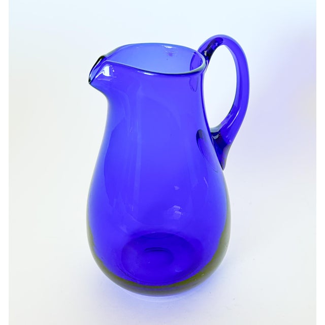 Lovely large cobalt blue blown glass pitcher with applied handle. Polished pontil mark on the bottom. It features a nice...
