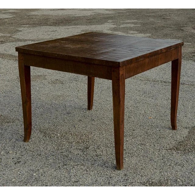 Square table with spiked stems plated in italian walnut from the early 1800s. The drawer is missing and the top has a...