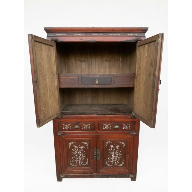 Stunning vintage Chinese cabinet with intricate white floral inlay. This beautiful piece features a rich red lacquer...
