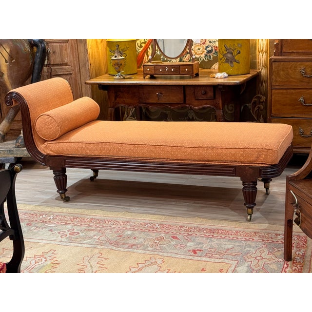 A period English Regency recamier with scrolled end support and a loose cylindrical bolster, upholstered in a geometric...
