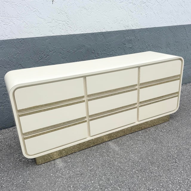 A sleek and sculptural Postmodern dresser showcasing a cream gloss laminate finish with softly rounded waterfall edges and...