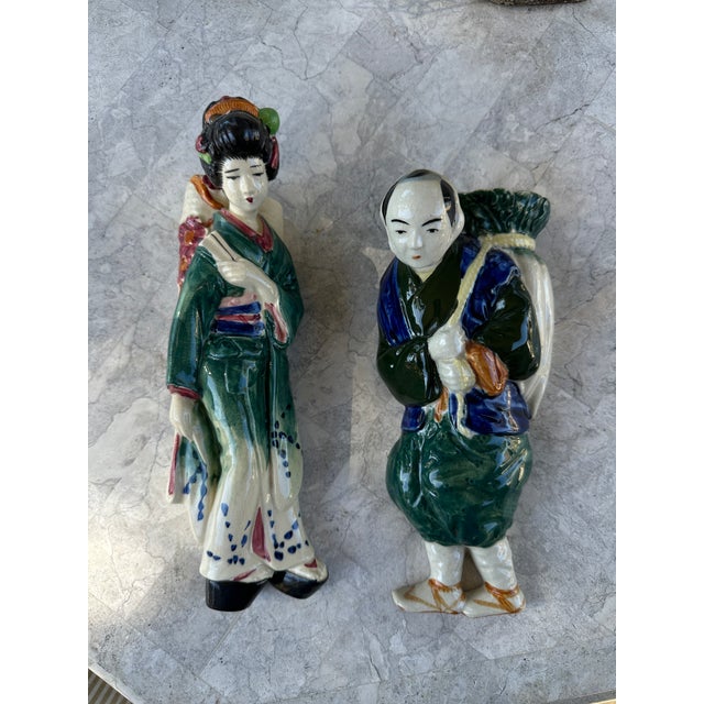 A decorative pair of vintage ceramic figural wall pockets depicting figures in traditional Asian dress. Each piece...