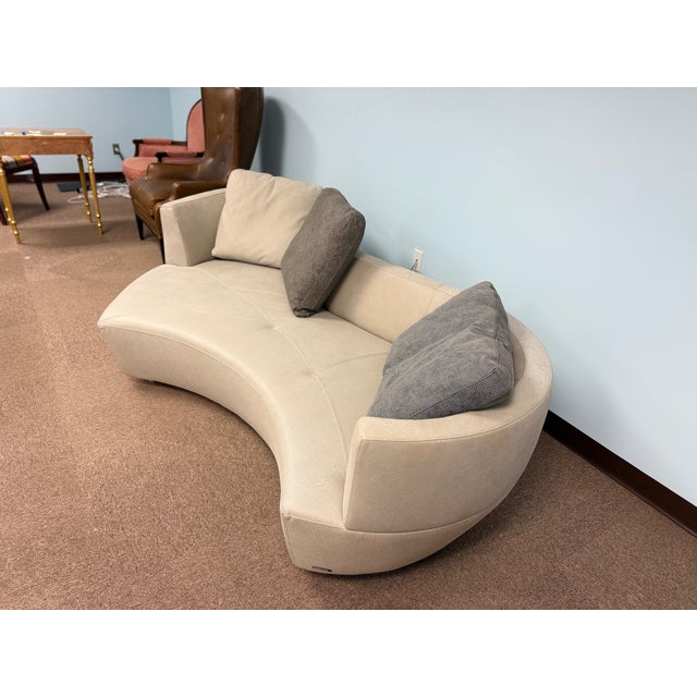 Modern curved upholstered sofa with a smooth crescent silhouette and clean lines. Finished in light beige fabric and...