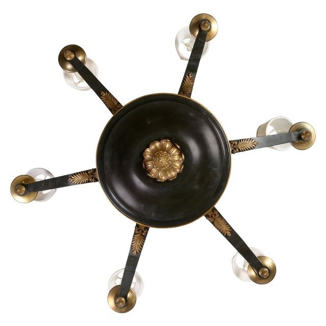 An Empire style, vintage six light tole chandelier with gilt accents and an arrow motif. Featuring six scrolling arms,...