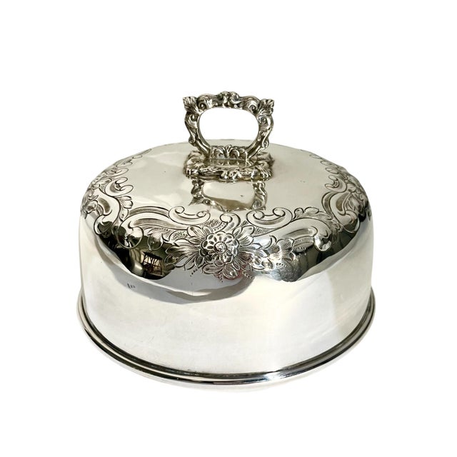 An elegant antique French silver plate serving dome, beautifully adorned with intricate floral and scrollwork detailing....