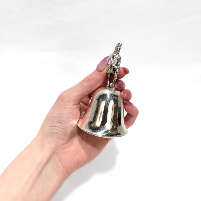 A fine signed table bell. By Cartier. In sterling silver. With a figural handle in the form of a man wearing a jacket and...